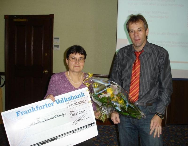 Thomas Simon, Vorstandsvorsitzender des Alport-Selbsthilfe e. V., übergibt die Spende in Höhe von 10.000 Euro an Dr. Heidrun Rhode vom Institut für Biochemie am UKJ. 