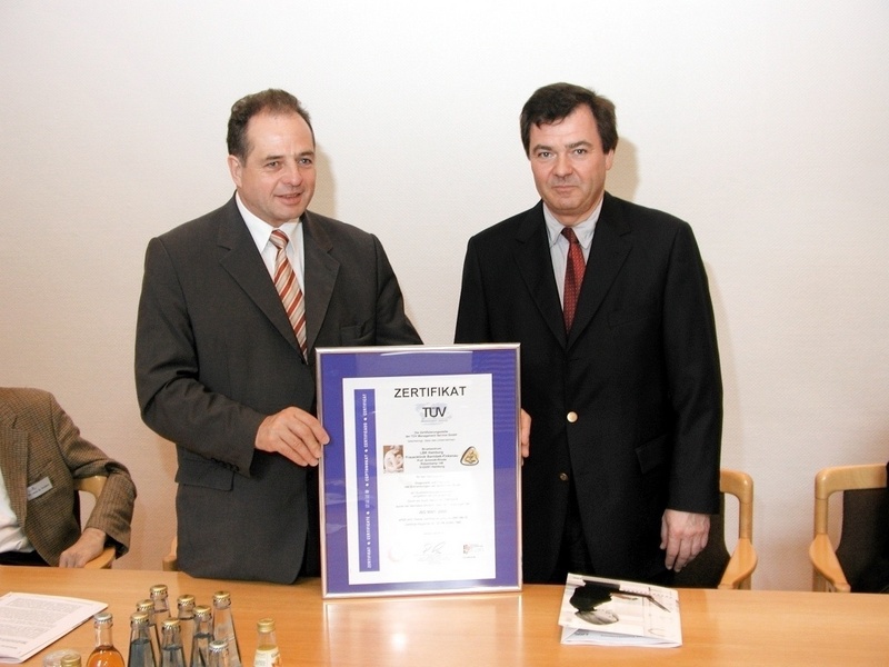TÜV-Auditor Dr. Wolfgang Tiedemann überreicht Prof. Dr. Peter Schmidt-Rohde die Zertifizierungs-Urkunde.