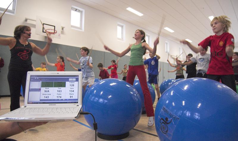 Im Chemnitzer Georgius-Agricola-Gymnasium haben die Wissenschaftler Drums Alive sowohl zur Projektarbeit als auch im Sportunterricht eingesetzt: Fünftklässler trommeln unter  Anleitung von Drums Alive-Erfinderin Carrie Ekins (l.).