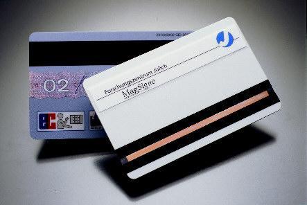 Alt und neu: Im Vordergrund der neue Magnetstreifen aus Jülich - ein fälschungssicheres Multi-Bit-System. Es kann mit herkömmlicher Magnetlesetechnik entziffert und auf Echtheit geprüft werden. Foto: Forschungszentrum Jülich