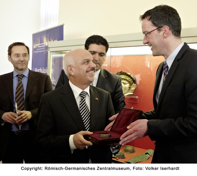 Feierliche Übergabe der antiken Streitaxt durch Staatssekretär Michael Ebling an den Botschafter der Republik Irak Dr. Hussain Mahmood Fadhlalla Al-Khateeb im Beisein von Univ.-Prof. Falko Daim, Generaldirektors des RGZM 