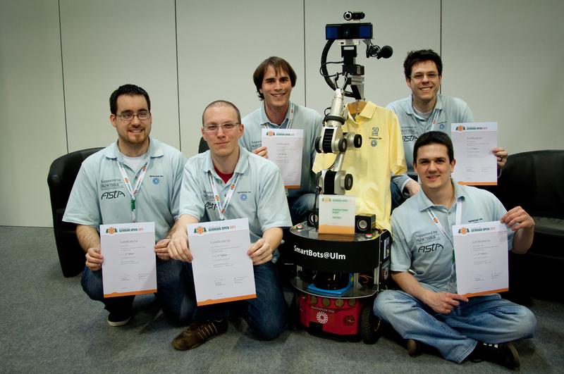 Das Team SmartBots@Ulm der Hochschule Ulm wurde mit dem Serviceroboter Kate Vizemeister in der Kategorie @Home beim RoboCup German Open 2011 in Magdeburg. Von links nach rechts: Benoit Sauts, Markus Stowasser, Manuel Wopfner, Jonas Brich und Markus Stix (rechts vorn). Nicht auf dem Bild das sechste Mitglied des Teams Andreas Falk.
