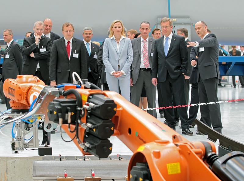 Prof. Bernd Mayer (3. von rechts) und Dr. Dirk Niermann (rechts) führen dem Bundespräsidenten die automatisierte klebtechnische Montage am Flugzeugrumpf vor.