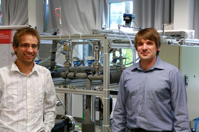 Dipl.-Ing. Markus Preißinger (li.) und Dipl.-Ing. Florian Heberle in einem Labor des Zentrums für Energietechnik (ZET) an der Universität Bayreuth. Im Hintergrund der Teststand zur Messung von Wärmeübergangskoeffizienten bei Verdampfung und Kondensation.