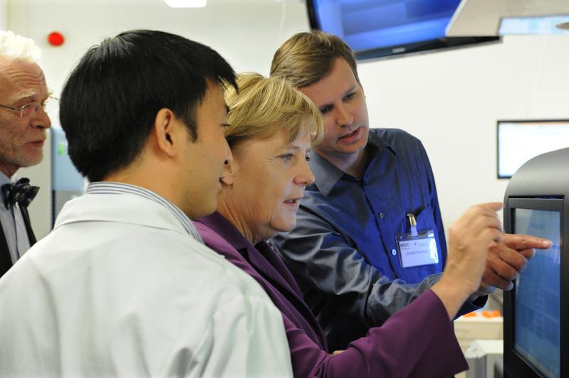 Bundeskanzlerin Angela Merkel lässt sich im Berliner Institut für Medizinische Systembiologie (BIMBS) des Max-Delbrück-Centrums für Molekulare Medizin (MDC) eines der neuesten Sequenziergeräte für DNA-Analysen erklären von dem aus Berlin stammenden Dr. Jonas Korlach (r.), Mitentwickler des DNA-Analysegeräts des US-Technologieunternehmens Pacific Biosciences und Dr. Wei Chen (l.), Leiter der Genomikplattform des BIMSB. Korlach ist auch Mitbegründer des Unternehmens in Menlo Park Kalifornien. 