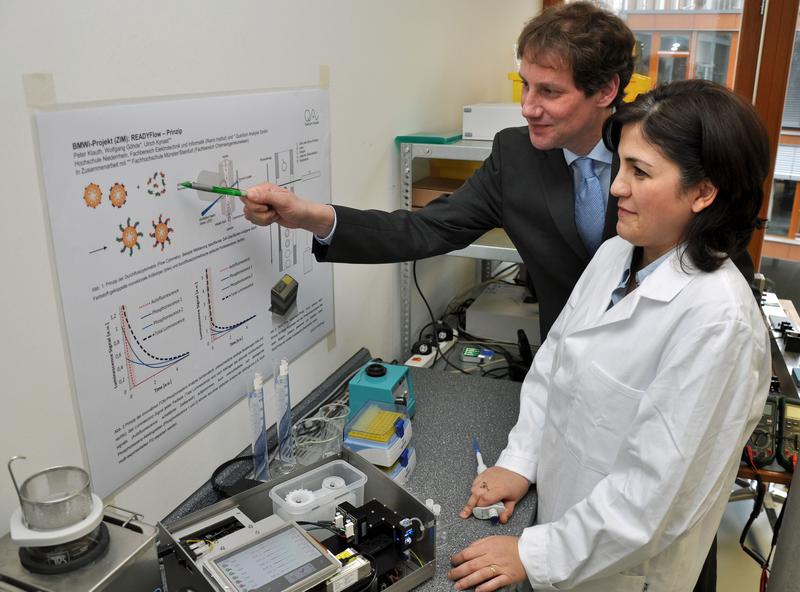 Dr. Wolfgang Göhde, Geschäftsführer der Quantum Analysis GmbH, betrachtet mit seiner Mitarbeiterin Aygül Aliyeva das ReadyFlow-Prinzip. Dabei werden Zellen oder Partikel analysiert, die mit hoher Geschwindigkeit einen Lichtstrahl passieren. Foto: TFM / Martin Rühle 