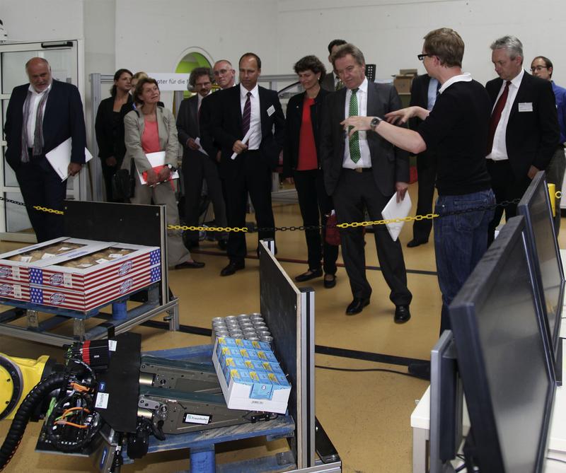 Hendrik Mütherich erklärt das Prinzip des Aufwälzgreifers im Roboterversuchsfeld.