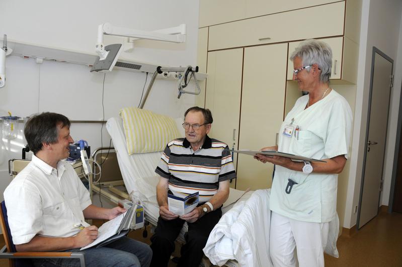 Sich Zeit nehmen - Dr. Andreas Jülich und Schwester Simone Schröder klären Friedrich Diederich über die Möglichkeiten der modernen Schmerztherapie auf. Sie entscheiden sich zusammen für den Einsatz einer kleinen tragbaren Pumpe, über die während der ersten Tage nach der Operation die schmerzlindernden Medikamente verabreicht werden.