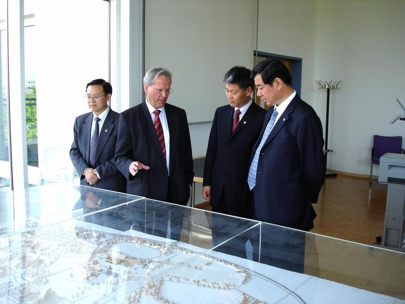 Das Bild zeigt Universitätspräsident Professor Ruppert bei der Erläuterung des Bayreuther Campus an dessen Modell. Rechts Vizegouverneur Wang, daneben Professor Dr. Liu Dezhang, Dekan der Fakultät für Interkulturelle Germanistik in Qingdao, der auch in ausgezeichnetem Deutsch als Übersetzer auftrat, sowie links der Rektor der Universität Qingdao, Professor Dr. Xia Lin Hua.