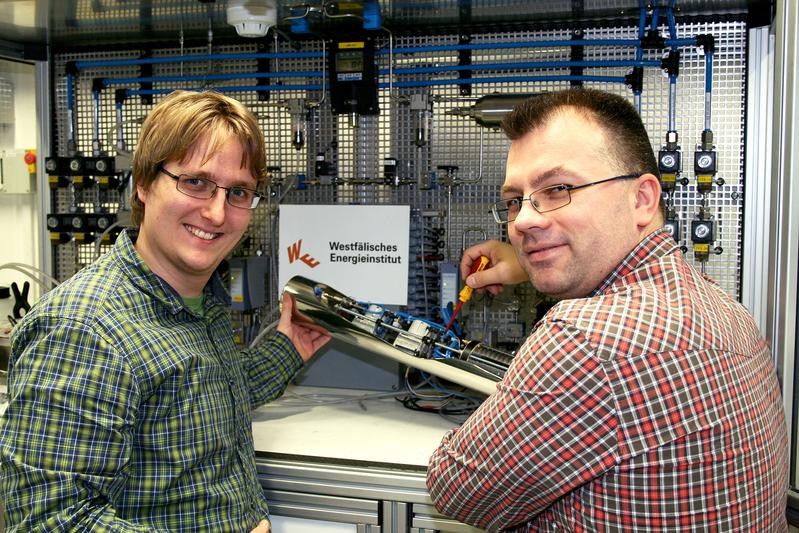 Die Mitarbeiter Ulrich Rost (l.) und Cristian Mutascu zeigen ein zylinderförmiges Brennstoffzellensystem, mit dem beispielsweise ein Erdbebensensor in einem Bohrloch mit Energie versorgt werden kann. Als "Abgas" entsteht bei der Energieproduktion lediglich Wasserdampf, der dem Untergrund nicht schadet. Foto: WH/MV, Abdruck honorarfrei