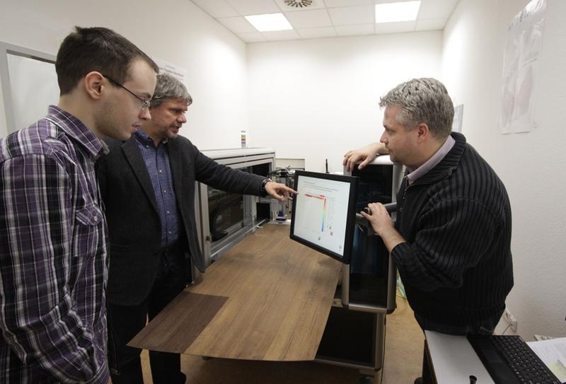 (v.l.n.r.): Projektmitarbeiter Markus Schumacher, M.Sc. (Absolvent des Studiengangs Angewandte Mathematik an der HTWK Leipzig), Prof. Dr.-Ing. Michael Reiche (Verfahrenstechnik der Medienvorstufe) und Prof. Dr. rer. nat. Lutz Engisch (Werkstoffe) am TopoScan-3D-Scanner – eingescannt wird ein Holzfurnier, um den Ablauf vom Muster zum fertig gedruckten und geprägten Produkt zu testen.