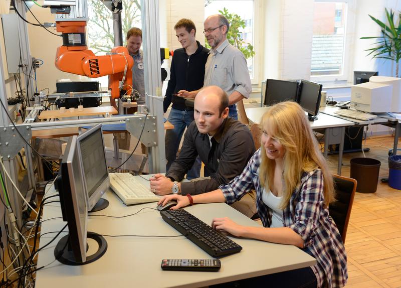 Mechatronik-Studierende der HS Osnabrück haben einem Industrie-Roboter „beigebracht“, Ostereier zu palettieren. Rund 160 Arbeitsstunden hat jedes der vier Teammitglieder in das Projekt investiert. Unser Bild zeigt (von links): Matthias Speer,  Alexander Krieger, Projektbetreuer Heinz-Hermann Hillbrand sowie Sebastian Werning und Insa Maßmann.