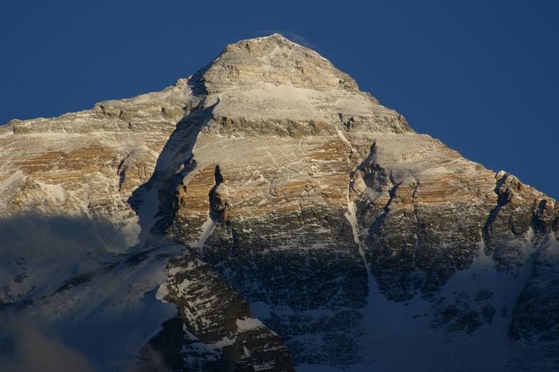 Nordseite des Mt. Everest, vom Rongbuk-Tal (Tibet) aus gesehen. Die Abscherung, die den Kalk des Gipfelbereichs von dem darunterliegenden gelben Marmor trennt, ist gut zu erkennen. Die Proben für die Studie wurden im untersten dunklen Bereich des Massivs gewonnen. 