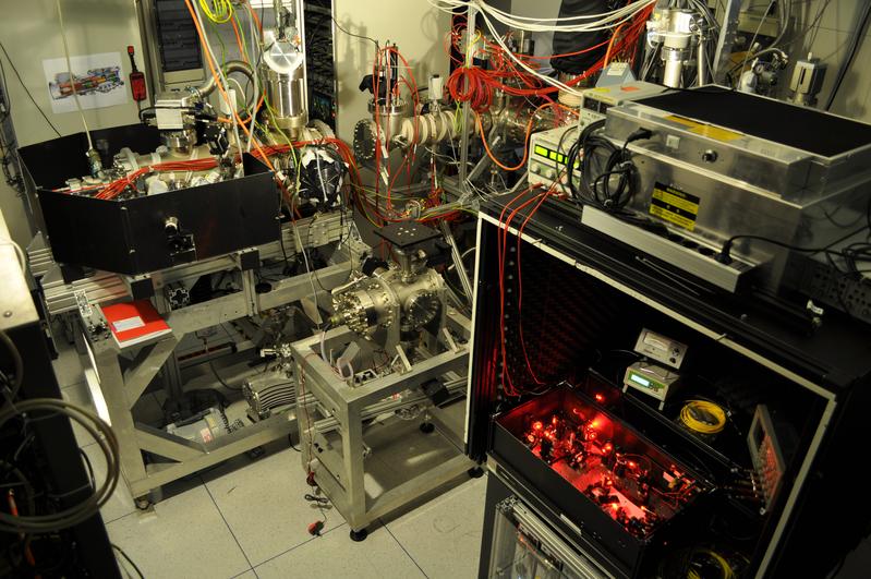 Abb. 2: Das neue CryPTEx-Ionenfallen-Labor am Heidelberger MPI für Kernphysik. Vorn rechts der Laser zur Kühlung der Ionen, hinten rechts die Elektrostrahl-Ionenquelle für hochgeladene Ionen und links die CryPTEx-Ionenfalle.