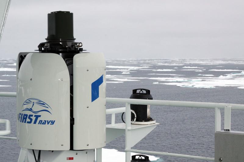 Der FIRST Navy Wärmebildgeber ist im Krähennest in einer Höhe von ca. 28 Metern über dem Wasser auf einer hochstabilisierten Plattform (weiße Basis) installiert. Der Sensorkopf (grün) rotiert mit 5 Umdrehungen pro Sekunde. Durch die Aufbauten von Polarstern entstehen im Krähennest oft sturmähnliche Windbedingungen, während die Temperaturen auf bis zu minus 30°C sinken können. Beides stellt höchste Anforderung an das System.