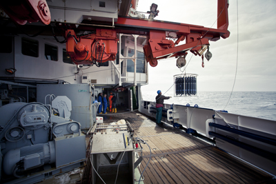 Ein Besatzungsmitglied des FS Polarstern lässt einen Wasserkranzschöpfer, auch CTD-Sonde genannt, für eine Messung ins Meer hinab.