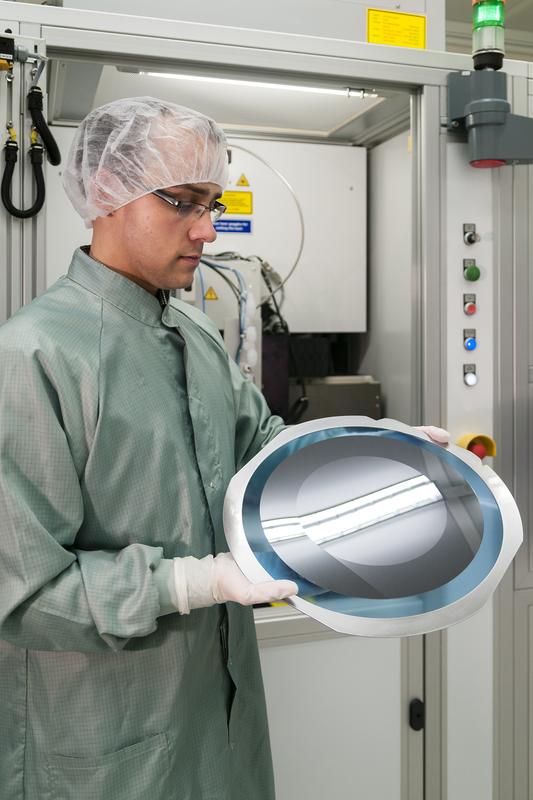 Dr. Mathias Koitzsch im Reinraumlabor des Fraunhofer IISB mit einer durch Thermisches Laserstrahlseparieren (TLS) aus einem 300 mm-Wafer nachträglich ausgeschnittenen 200 mm-Siliciumscheibe.