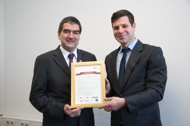 Prof. Dr. Benedikt Hackl (DHBW Ravensburg) überreicht Dominik Bartmuß, Vice President HR (Voith Industrial Services, Bereich Automotive), die Urkunde.
