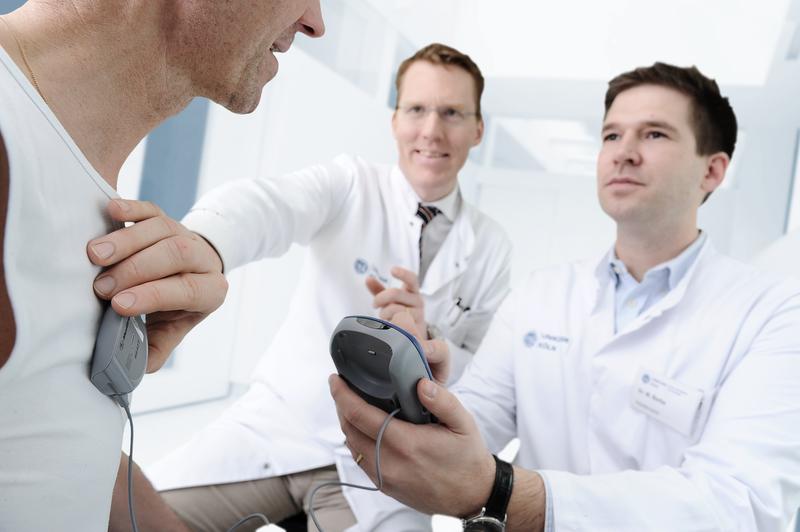 Prof. Dr. Lars Timmermann (mitte) und Dr. Michael Barbe (rechts) überprüfen am Patienten die individuellen Stimulationsparameter.