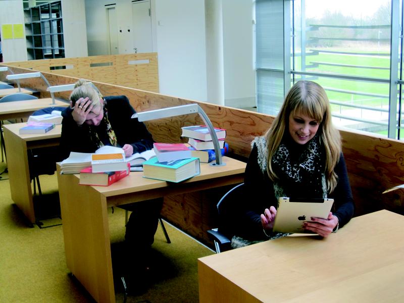 Studentin lernt mit dem Tablet in der Bibliothek
