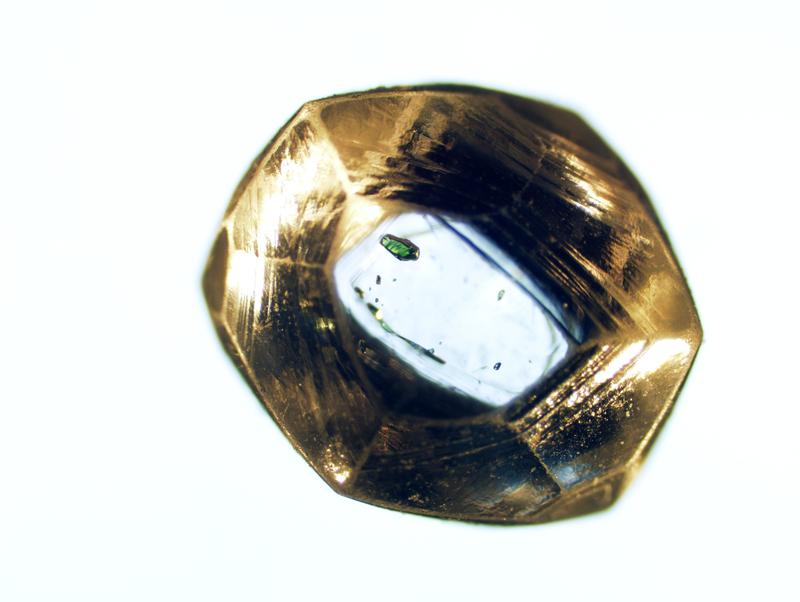 Diamantkristall (knapp 5 mm groß) von Namaqualand, Republik Südafrika. Im Zentrum sieht man mehrere Mineraleinschlüsse, darunter einen grünen Chrom-Diopsid. 