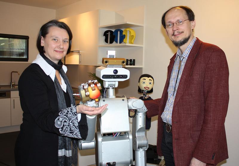 Prof. Dr.-Ing. Britta Wrede und Prof. Dr. Helge Ritter begrüßen den Roboter der Firma Meka Robotics. Der Service-Roboter soll mit einer Variante des Flobi-Kopfes (Hintergrund) ausgestattet werden. 