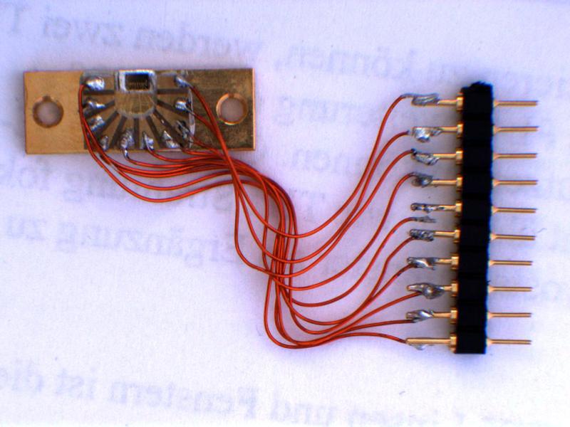 Auf einer Wärmesenke montierter Laser-Chip. Rings um den Chip befindet sich ein U-förmiges Leiterplättchen, über das die elektrische Verbindung mit den Zuleitungsdrähten hergestellt wird.