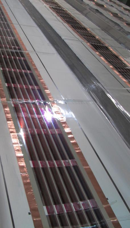 Ausschnitt der fertigen organischen Solarmodule (rötliche Streifen) auf der Membranfolie (weiß). ©Vladimir Kozhukharov, UCTM, Bulgarien.
