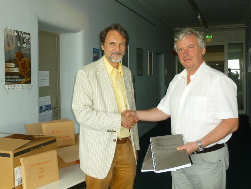 Prof. Dr. Rolf Pohl (rechts) überreicht dem Dekan des Fachbereichs Betriebswirtschaft, Prof. Dr. Gunter Kürble, die Akkreditierungsunterlagen