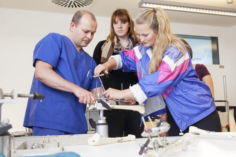 Dr. Christoph Riepl (links) übt mit Teilnehmern der Sommerakademie, wie man Knochenbrüche schnell von außen mit sogenannten externen Fixateuren stabilisieren kann.