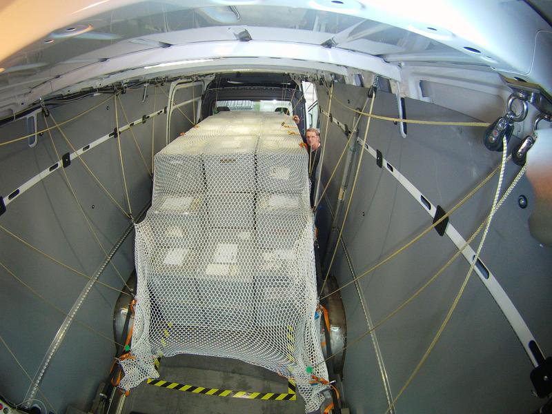 Ein sich flexibel anpassendes Netz überspannt das Transportgut, das über Rückholseile und durch Umlenkrollen innerhalb weniger Sekunden wieder unter die Laderaumdecke gehoben werden kann.