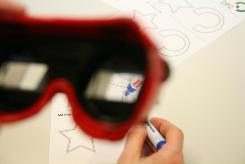 Dr. Pierre Morel zeigt mit Hilfe einer Umkehrbrille, wie man dem Auge die entgegengesetzte Bewegung zeigt, als man sie eigentlich ausführt.