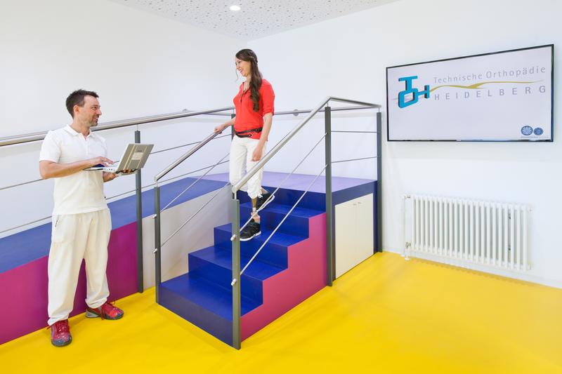 Eine junge Patientin nach Oberschenkelamputation gemeinsam mit ihrem Orthopädietechniker bei der dynamischen Anprobe und Justierung ihrer Prothese.