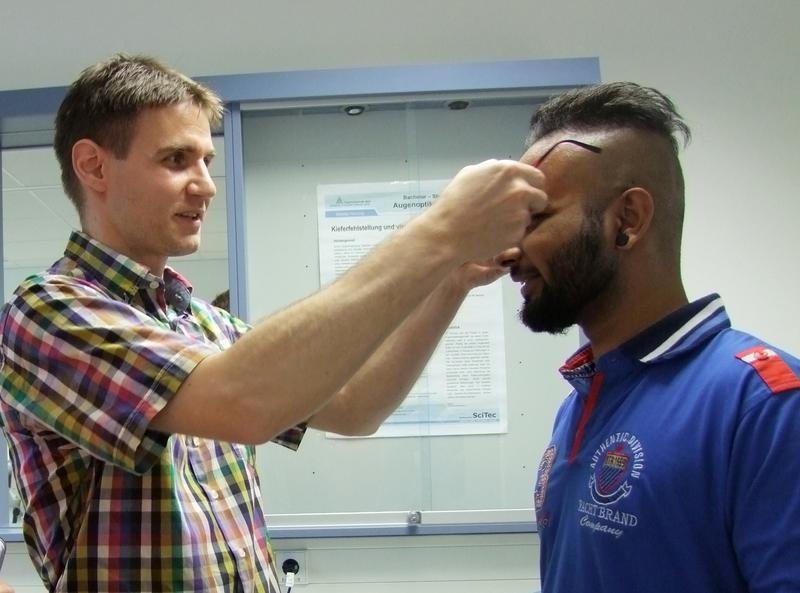 Der Sponsor der Brille, Sebastian Marx, li., passt Dithin N. die neue Brille an