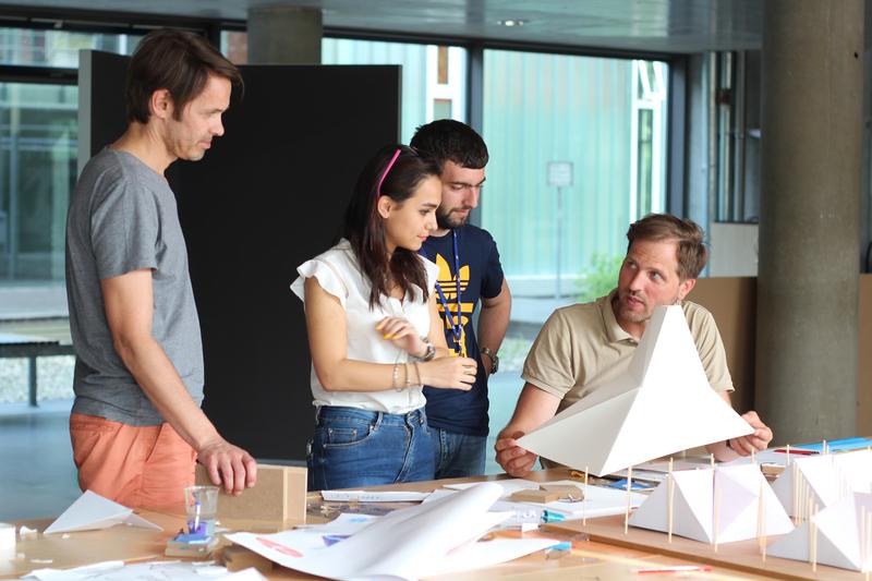 Die Dozenten Mark Pepper (rechts sitzend) und Markus Sohst (links stehend) erarbeiten mit den Teilnehmern der Internationalen Sommerakademie Wismar mobile Flüchtlingsunterkünfte