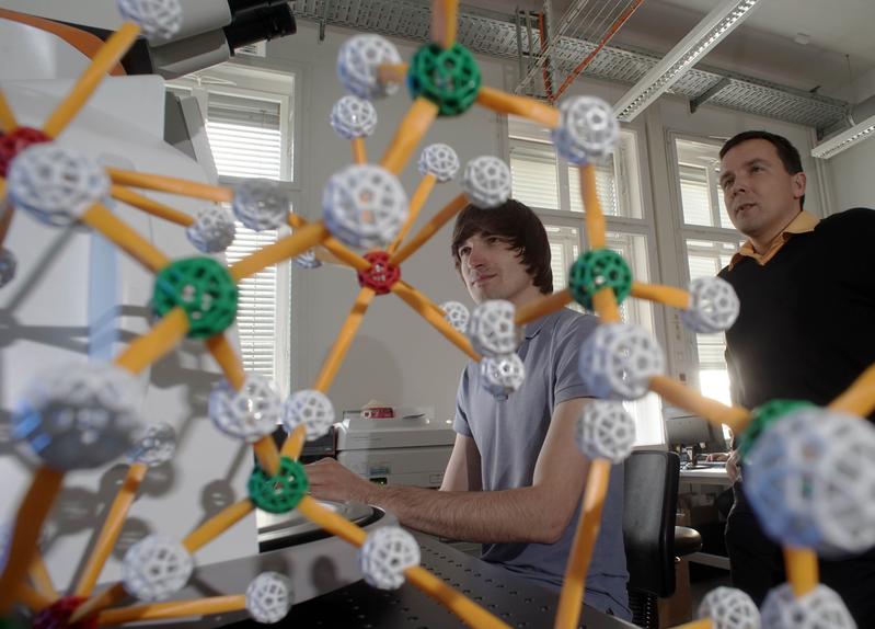 Der Sprecher des gerade verlängerten Schwerpunktprogramms Prof. Dr.-Ing Lothar Wondraczek (r.) und Doktorand René Limbach in einem Labor der Universität Jena; im Vordergrund ein Atommodell von Glas. 