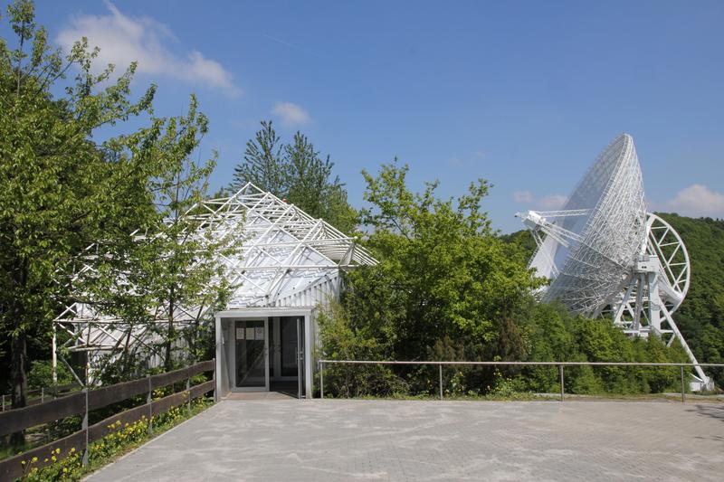 Besucherpavillon am Radio-Observatorium Effelsberg mit 100-m-Teleskop im Hintergrund. Die Live-Messungen am Astronomietag werden in den Besucherpavillon übertragen.