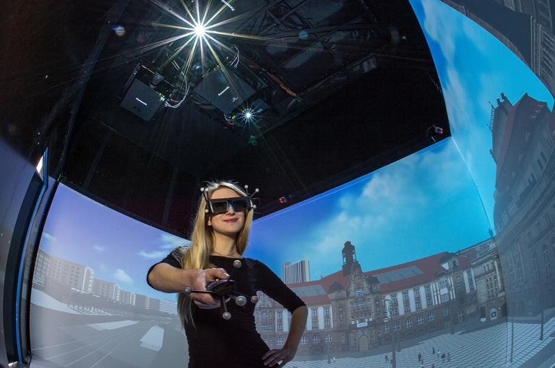 Studentin Eva Zurbrügg testet den Immersionseindruck innerhalb des virtuellen Stadtrundganges der Stadt Chemnitz. Die an der Decke des Containers angebrachten Projektoren sorgen für den 3D-Eindruck.