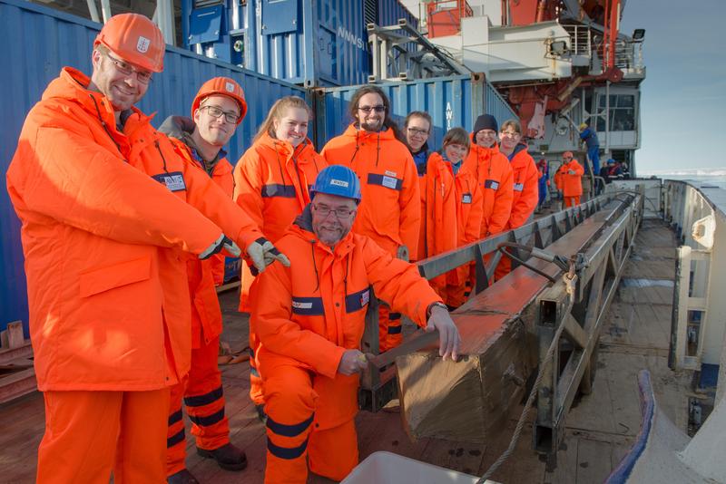 Freude über eine gelungene Sedimentkern-Bohrung: Polarsternfahrtleiter Prof. Dr. Rüdiger Stein (blauer Helm) und sein Team posieren neben dem Kastenlot, welches den Sedimentkern enthält. 