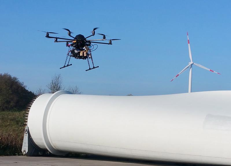 Beispielabbildung: Der „InspektoKopter“-Prototyp bei der Rotorblattbefliegung einer Windenergieanlage (Foto: Netzwerk „InDiWa“, FuE-Projekt „InspektoKopter“).