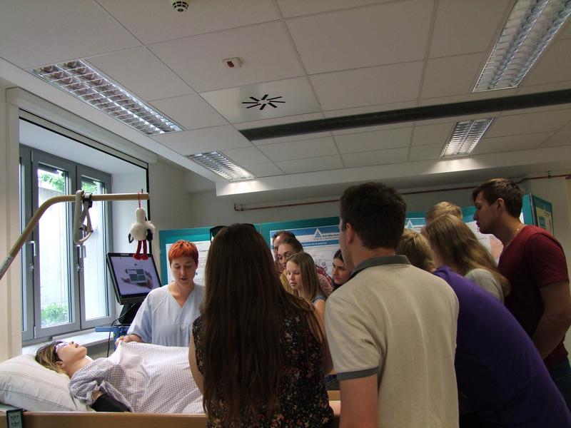 Renate Frank, li. stehend, erläutert am Simulationsbett eine Geburt