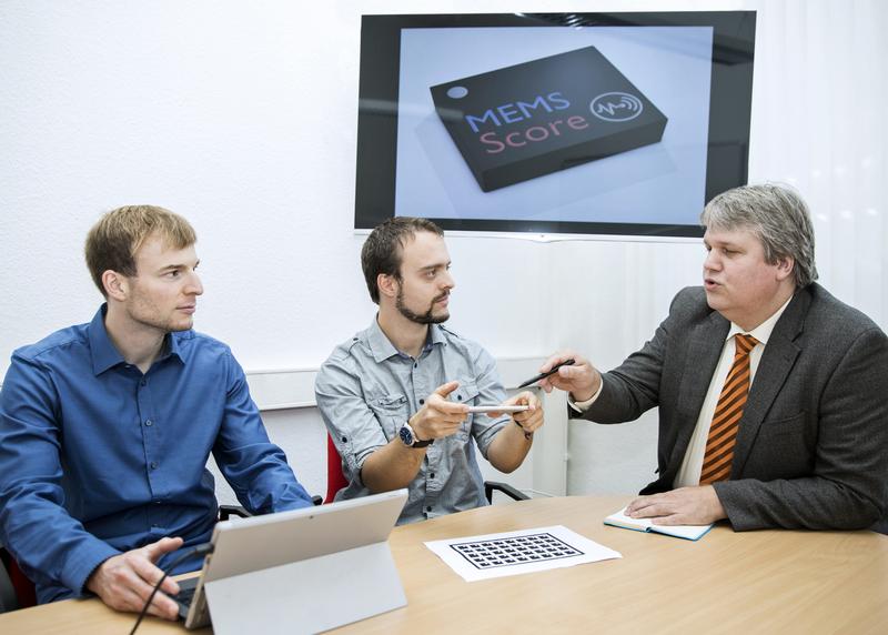  Professor Christian Haubelt (re) diskutiert mit den beiden Forschern Dr. Lars Middendorf (li) und Nils Büscher die Funktionsweise der MEMS Score App. 