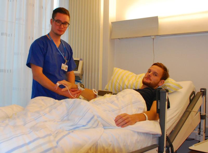 Pfleger Lukas Großmann legt bei einem Patienten eines der kabellosen Messgeräte an, mit denen die Vitalfunktionen erfasst werden können.