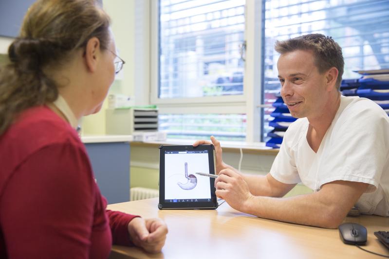 UKL-Mediziner Dr. Stefan Niebisch erläutert Patientin Bettina Kahler, an welcher Stelle der Speiseröhre sich das flexible Band aus magnetischen Titankügelchen befindet.