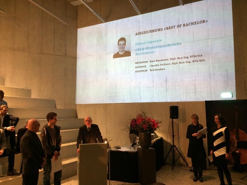 Fabian Capararo (mit Couvert) lauscht der Laudatio von Jury-Präsident Anton Steurer. Er wird begleitet von Institutsleiter Prof. Dr. Imad Lifa.