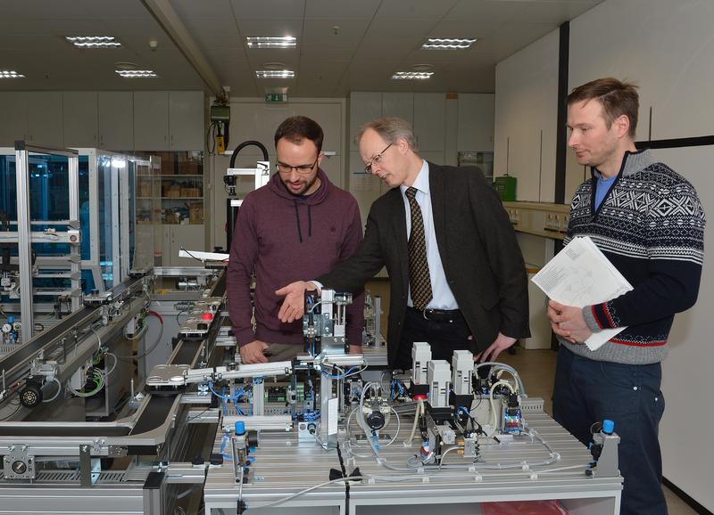 Alexander Fay (Mitte), Professor für Automatisierungstechnik, mit Mitarbeitern am Modell einer Fertigungsanlage
