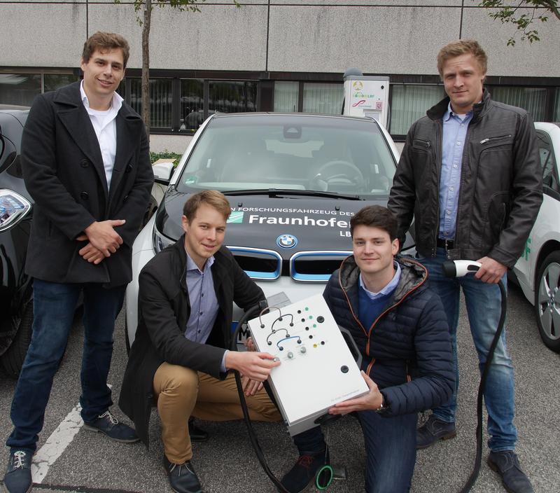 Das Studententeam der Hochschule Darmstadt vor Forschungsfahrzeugen und der Ladesäule des Fraunhofer LBF. 