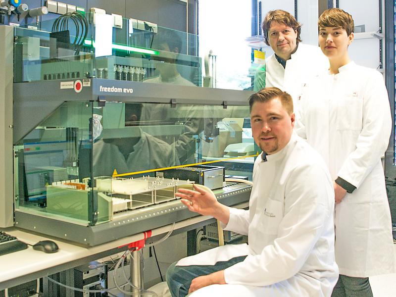 At the pipetting robot in the Life & Brain research center: Dr. Andreas Forstner (seated at the front), associate professor (Privatdozent) Dr. Rupert Conrad and psychologist Stefanie Rambau. 