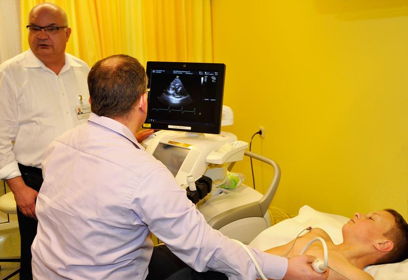 Prof. Dr. Deniz Kececioglu (l.) und PD Dr. Kai Thorsten Laser mit Testpatient Jan-Philipp (12) beim Herzultraschall