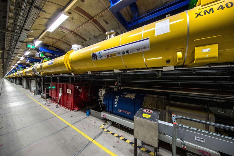 View into the 2.1-kilometre long accelerator tunnel of European XFEL with the yellow superconducting accelerator modules hanging from the ceiling.